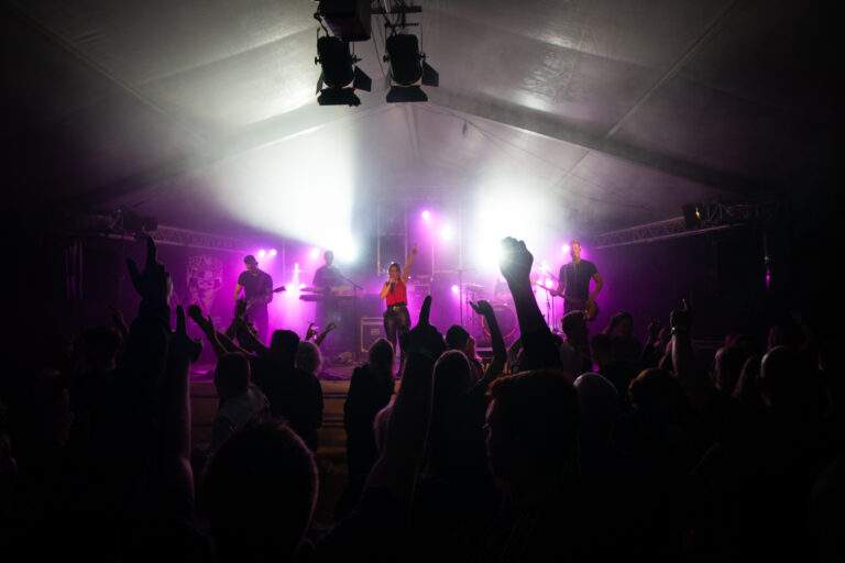 The Bandits feestband op podium met publiek in tent met paarse verlichting